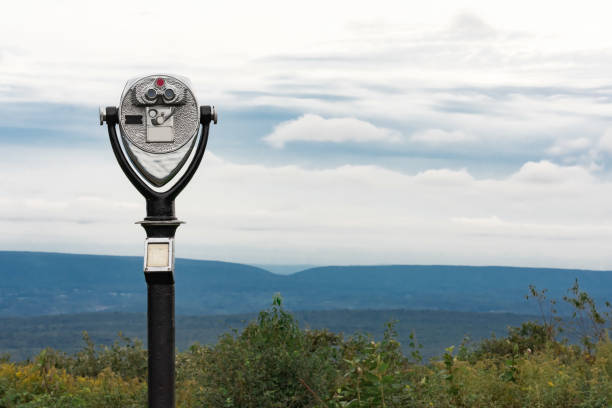 Coin operated viewfinder high on mountain looking at scenic park view during the day