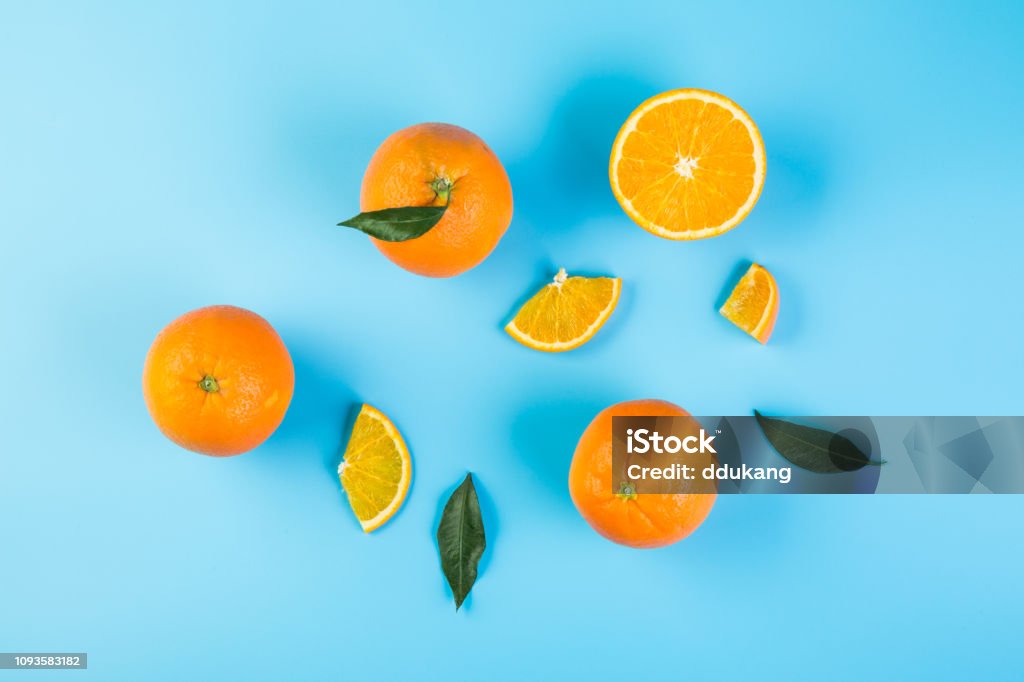 Healthy food. Sliced orange with green leaves on blue background, top view Slices of orange with leaves Orange - Fruit Stock Photo