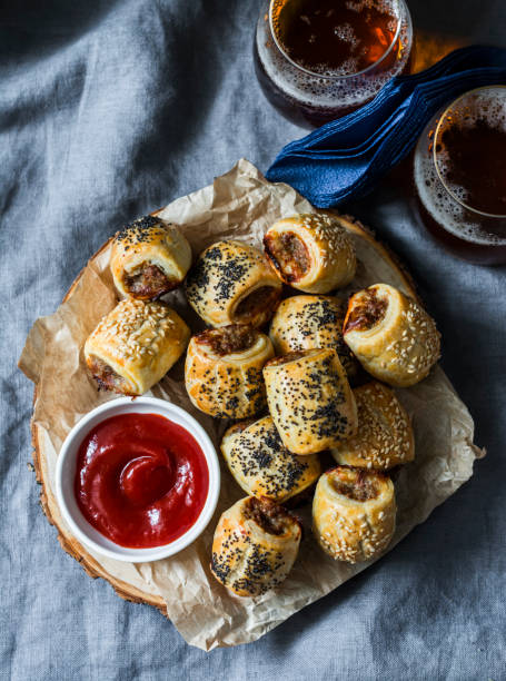 istock Served appetizers table - minced puff pastry rolls and beer on grey background, top view. Flat lay. Sausage rolls 1093585712