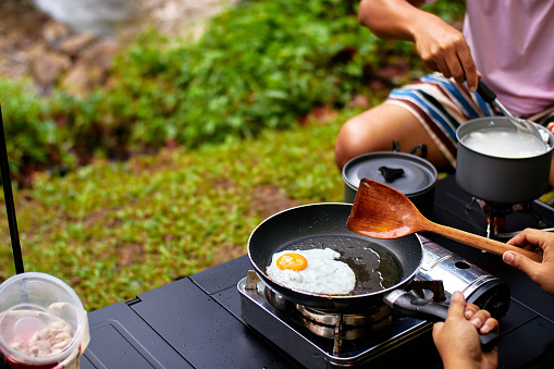 Frying egg while camping and outdoor picnic
