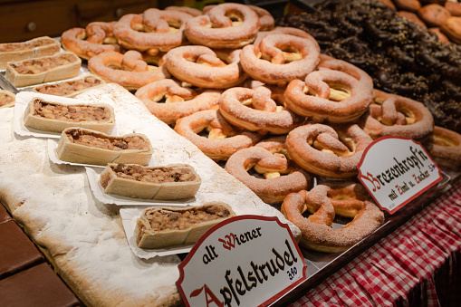 Display of traditional doughnuts on sale at Christmas market stall in Austria (translation: Old Viennese apple strudel; brezen doughnut with cinnamon and sugar)