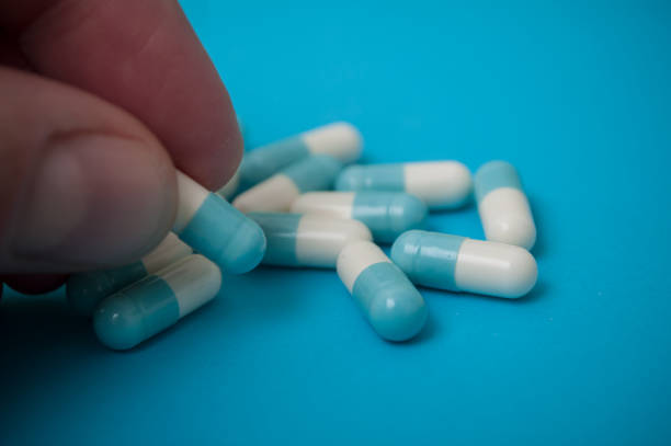 istock blue capsules in finger on blue background 1093590646
