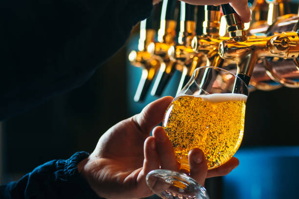 nahaufnahme von barkeeper gießen bier vom fass im glas - trinkglas fotos stock-fotos und bilder