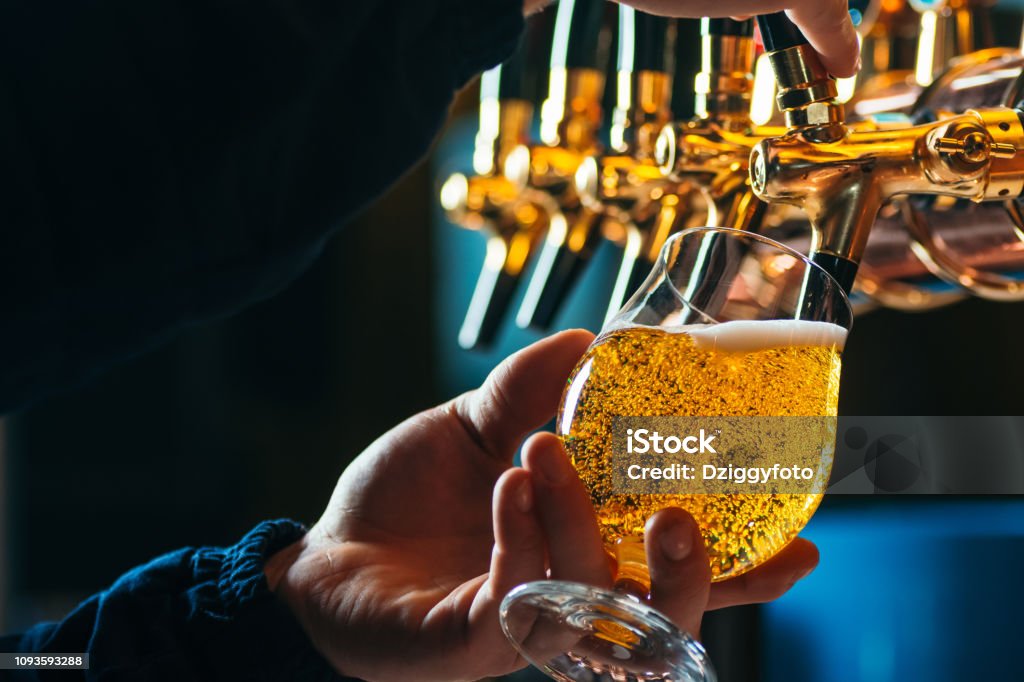 Close up of bartender pouring draft beer in glass Beer - Alcohol Stock Photo