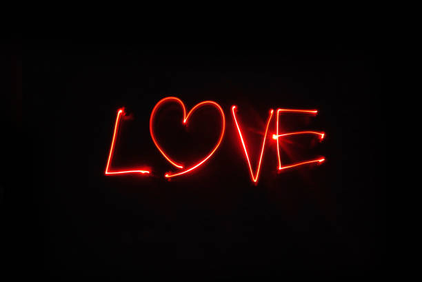Love- Light painting drawing with red LED lights on a black background. The letter o has been replaced with a heart. Studio shot