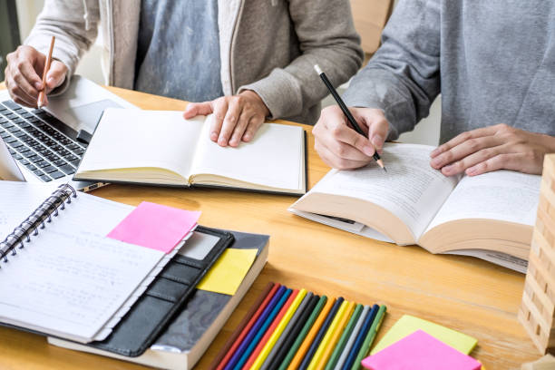 istock Education, teaching, learning, technology and people concept. Two high school students or classmates with helps friend do homeworks learning in classroom, Tutor books with friends 1093608820
