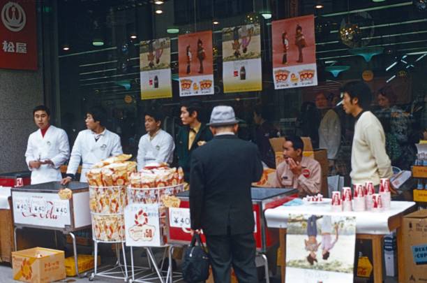 Tokyo, Honshu, Japan, 1975. Coca Cola and Chips promotion booth with male sellers in front of a shopping mall in Tokyo's Ginza shopping street.