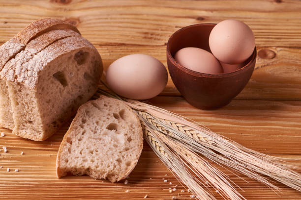 istock fresh delicious bread, concept for baking. Eggs in clay bowl and wheat sprouts on wooden table. concept home teste 1093617838