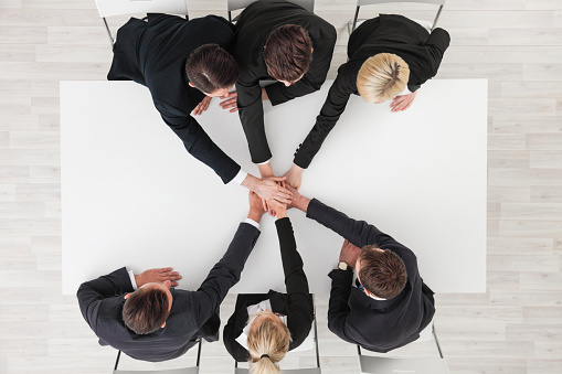Directly below shot of business team stacking hands over white table background