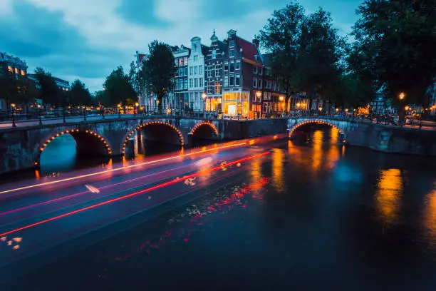 Amazing Light trails and reflections on water at the Leidsegracht and Keizersgracht canals in Amsterdam at evening. Long exposure shot. romantic city trip concept.
