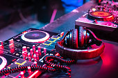 DJ music console in bright colors of light in night club