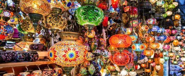 Beautiful lamps in Grand Bazaar, Istanbul, Turkey. Panoramic view of colorful oriental gifts. Stained glass lamps in artisan market close-up. Arab and Turkish craft products in eastern bazaar.