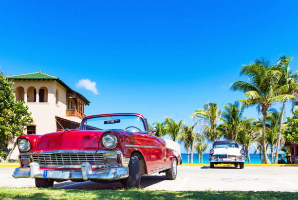 convertible rojo americano y un coche clásico blanco azul estacionado en la playa en varadero cuba - serie cuba reportaje - varadero beach fotografías e imágenes de stock