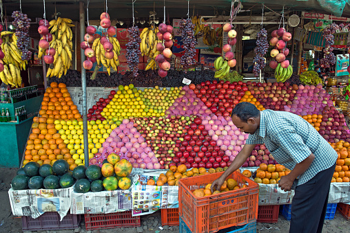 Cherthala,Kerala,India - January 15, 2013: Indian shop owner arranging mandarins in a crate in front of his market stall in Cherthala, a location in the Alappuzho district of Kerala, about 30 km south of Kochi.