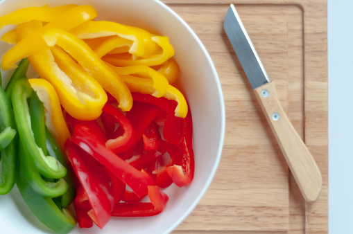 Sliced Bell Peppers in Bowl with Paring Knife on Cutting Board