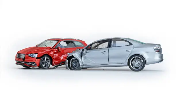 Photo of Two cars accident. Crashed cars. One silver sedan against one red coupé.