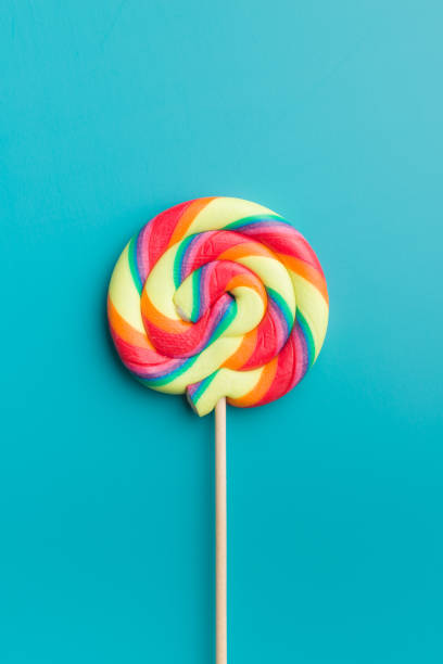 istock Colorful rainbow swirl lollipop on blue background. 1093651460