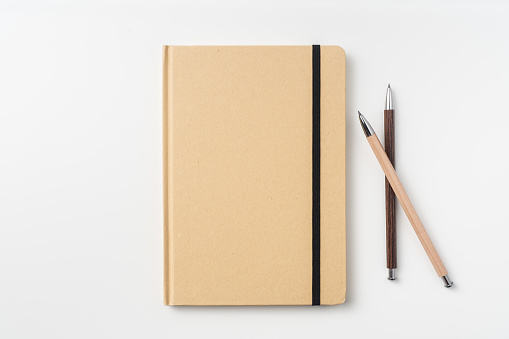 Design concept - Top view of kraft paper notebook and pencil isolated on background for mockup
