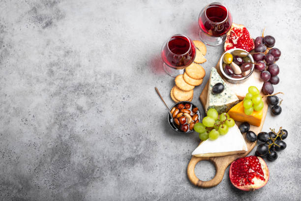 Selection of cheese and appetizers Selection of cheese and appetizers, wine in glasses, camembert, brie, cheddar, cracker, grapes, nuts, honey. Assorted mix of cheese on rustic wooden board with space for text, top view, close-up pomegranate in spanish stock pictures, royalty-free photos & images
