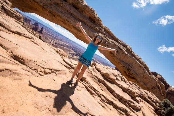 ângulo artístico de uma mulher atrativa do ajuste bonito que está com os braços para fora no arco do mesa no parque nacional de canyonlands - canyonlands national park utah mesa arch natural arch - fotografias e filmes do acervo