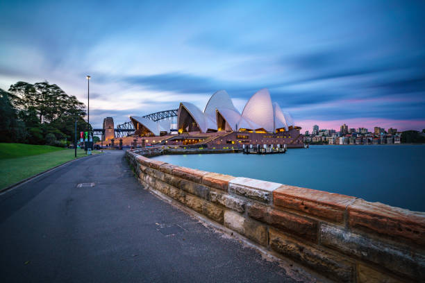 The spectacular cityscape of Sydney, Australia. Across the water we see the iconic form of the Sydney Opera House and beyond that the Royal Botanic Gardens and the towering skyscrapers of the CBD. A long exposure gives the water an unnaturally smooth appearance.