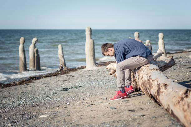istock Man picking up a pebble from the seashore 1093670416