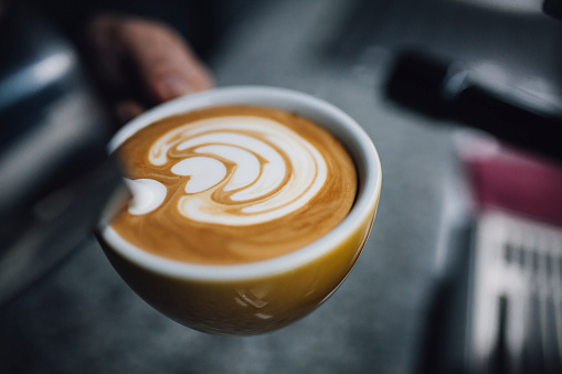 Barista holding coffee cup and make latte art coffee