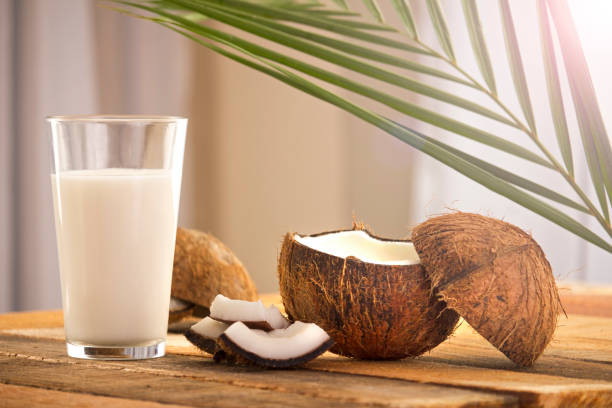 cocco su tavolo di legno - latte di cocco foto e immagini stock