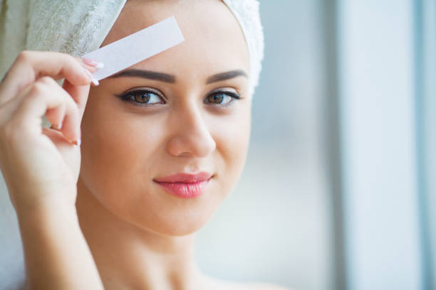 istock Beautician waxing young woman's eyebrows in spa center 1093683124