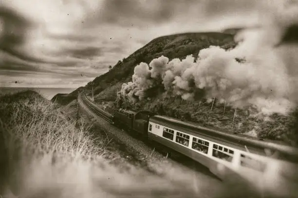 Photo of Old steam train, vintage locomotive with sea and mountain background  - retro photography