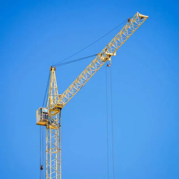 Construction crane on blue sky background. Copy space for text