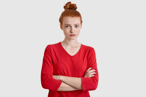 istock Studio shot of pleasant looking serious woman has stern expression, keeps arms folded, has red hair, listens something attentively isolated over white background. Redhaired female student poses indoor 1093688614