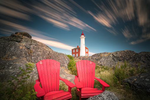 This is a long exposure of the Fisgard Lighthouse with red chairs in the foreground.