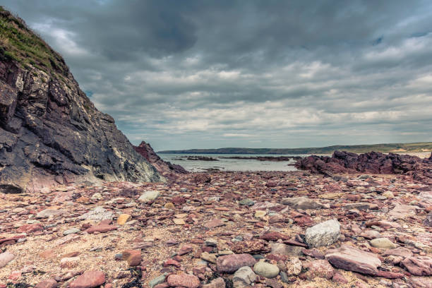 Beautiful scenery of dramatic Pembrokeshire coastline,South Wales, Uk.Stones and puddle on rocky beach during low tide.Moody sky over horizon.Scenic landscape of british coast.Nature image with copy space. hermoso paisaje de la espectacular costa de pembrokeshire, gales del sur, uk.stones y baño en la playa durante la marea baja. cambiante cielo sobre el horizonte. paisaje escénico de la costa británica. imagen de la naturaleza con espacio de copia.