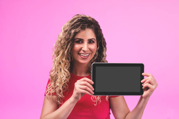 istock Cute young woman holding tablet on pink background. Mockup 1093702906