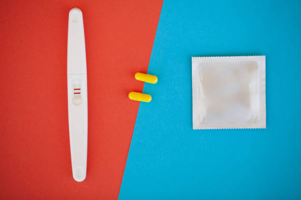 test de grossesse. le résultat est positif avec deux bandes et préservatif avec contraceptif sur fond coloré, pilule contraceptive, safe sex, santé concep - contraceptive sex education birth control pill condom photos et images de collection