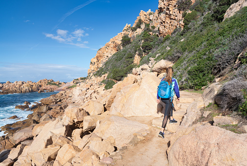 Female Tourist hiking to the beautiful Spiaggia di Li Cossi Beach Bay of the famous Costa Paradiso, Sardinia, Italy. Nikon D850. Converted from RAW.