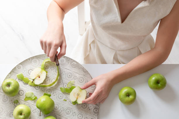 The girl is cutting green apples.