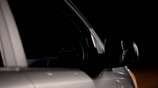 istock Businessman reflection in car mirror, driving through night city, back home 1093725552