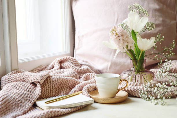 Cozy Easter, spring still life scene. Cup of coffee, opened notebook, pink knitted plaid on windowsill. Vintage feminine styled photo, floral composition with tulips, hyacinth and Gypsophila flowers. semana santa acogedor, escena de naturaleza muerta primavera. taza de café, abierto notebook, cuadros punto rosa en el alféizar de la ventana. foto vintage de estilo femenino. composición floral con tulipanes, jacintos y gypsophila flores.