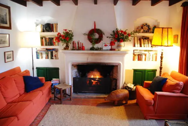 Fireplace beautifully decorated for Christmas Season in Spanish countryhouse. Fire is burning, cody lampe are set and Christmas ornamentos are visible around the scene