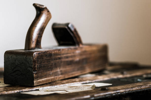 Antique wood hand plane resting on a trunk.  The hand plane is a tool for shaping and smoothing wood, using the craftsperson weight and strength to pass a blade within the place across the surface of the material being shaped.  This wooden version of the hand plane was in common use until the 1860s, when iron-cast hand planes began to be produced.