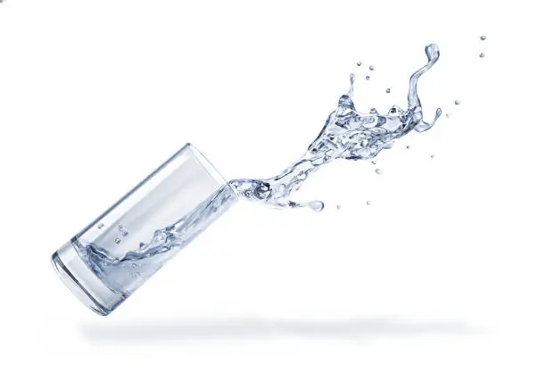 Photo of Glass with spilling water splash. Side view. On white background.