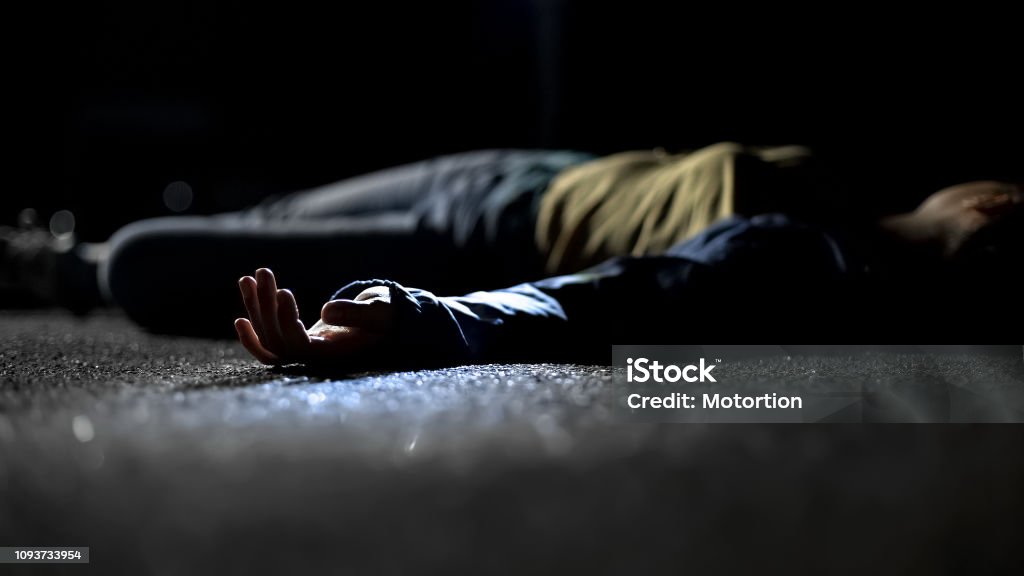 Bloody female victim of deadly car accident lying on road, close-up view at body Murder Stock Photo