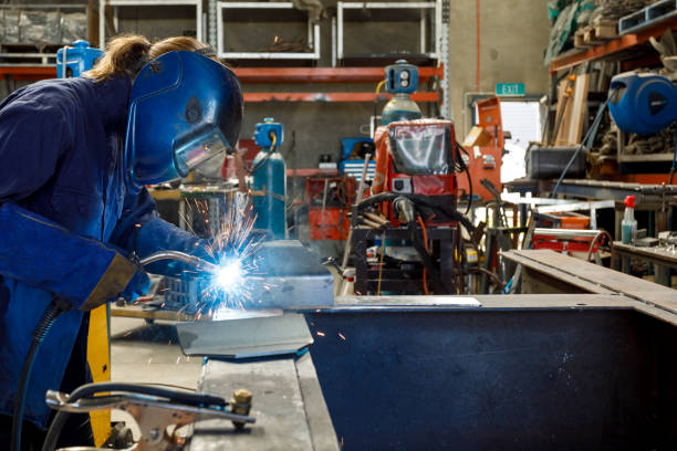 Female Welder Young Female Welder Working In Factory Wearing Protective Safety Gear automatic welding torch stock pictures, royalty-free photos & images