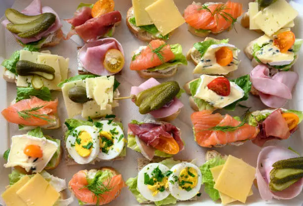 various canapes with egg, cheese, ham and salmon on a tray at the cold buffet, high angle view from above