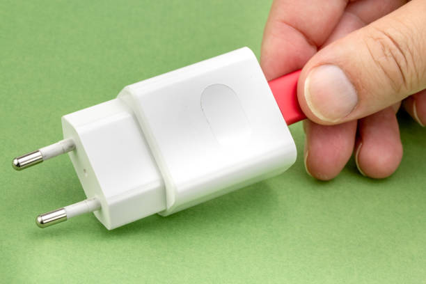 istock hand inserting a USB cable into a wall charger isolated on white background. 1093748434