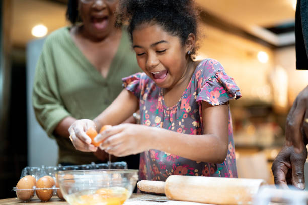 nonni afro ispanici-latini che insegnano a sua nipote come cucinare - baking flour ingredient animal egg foto e immagini stock
