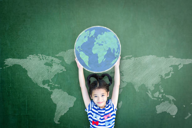 Educated school kid lifting world globe chalk doodle drawing on green chalkboard for education concept Educated school kid lifting world globe chalk doodle drawing on green chalkboard for education concept world childrens day stock pictures, royalty-free photos & images