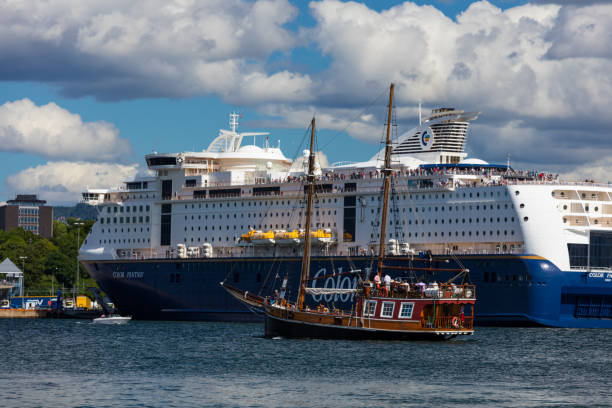 A modern ferry and an old ship are floating in the Oslofjord on a cloudy summer day. The Oslofjord is an inlet in the south-east of Norway, stretching from an imaginary line between the Torbjornskjar and Faerder lighthouses and down to Langesund in the south to Oslo in the north.
